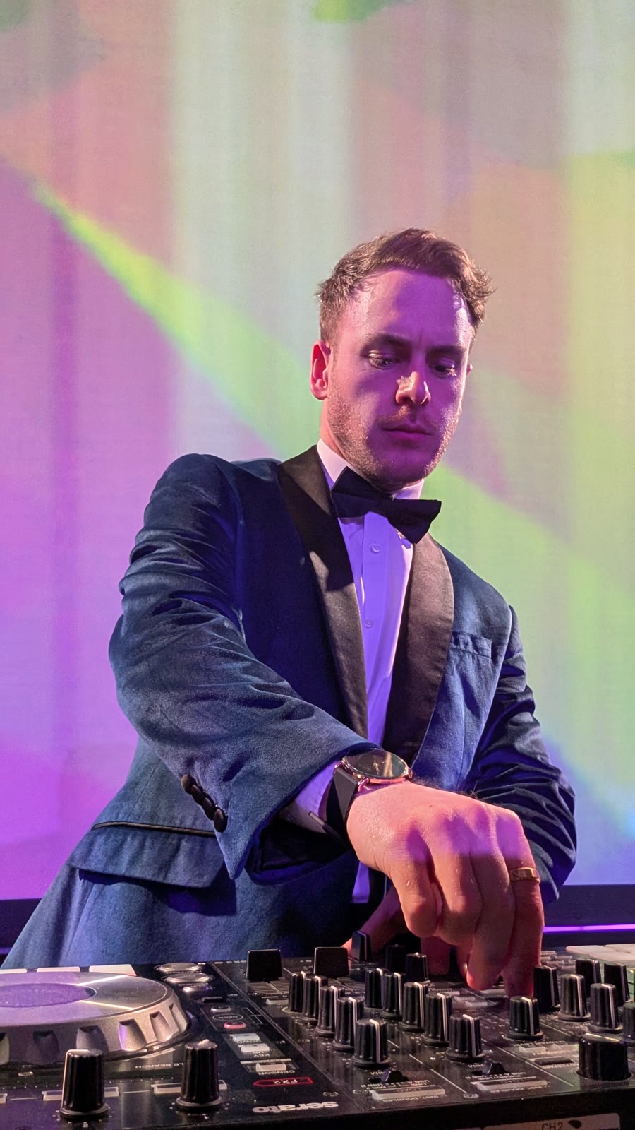 Tristan from Vision Mobile DJ behind the decks in a velvet dinner jacket