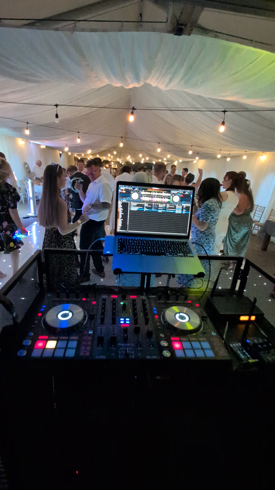 DJ booth set up in a festoon-lit wedding marquee